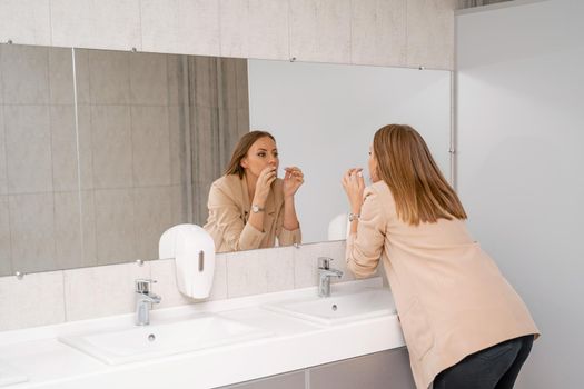 A woman washes her hands under running tap water in a public toilet