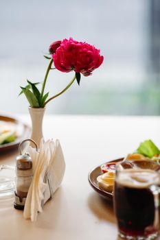 Beer cup standing near appetizers plate. Dark beer with thick high foam. Standing on smooth wooden surface of restaurant's or pub table. Looking mouthwatering. Cold and fresh. For friends company.