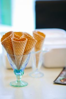 Close up of empty waffle cone in glass for ice cream. Tasty and sweet forms for ice cream in cafe on bar, perfect for summer heat. Concept of food and desert.