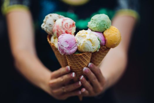 Close up of woman holding in hands and showing at camera many colorful ice cream, tasty, sweet, mouthwatering, perfect for summer heat. Girl with pretty nails eating sweet food.