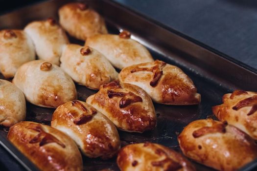 Delicious fresh baked flavored buns set made of sweet dough laying on big metallic dish standing in bakery kitchen. Looking mouthwatering, tasty. Laying near warm buns with cottage cheese feeling.