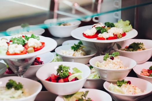 View of many round plates with tasty vegetables dish of salads with tomato, onion, zucchini, tomato and herbs. Big delicious for dinner in restaurant.