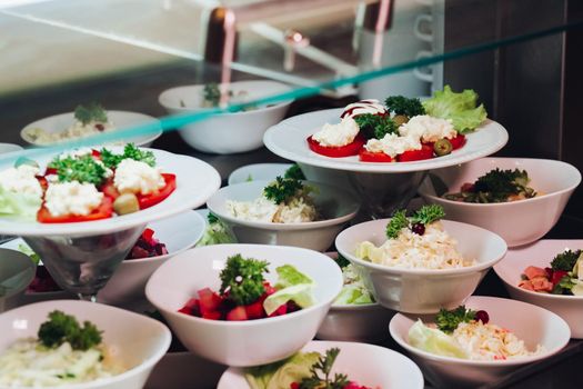 View of many round plates with tasty vegetables dish of salads with tomato, onion, zucchini, tomato and herbs. Big delicious for dinner in restaurant.