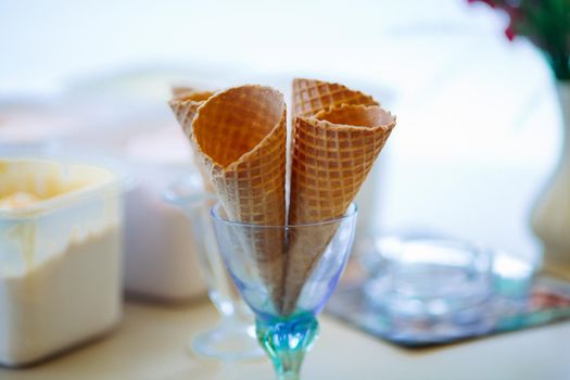 Close up of empty waffle cone in glass for ice cream. Tasty and sweet forms for ice cream in cafe on bar, perfect for summer heat. Concept of food and desert.