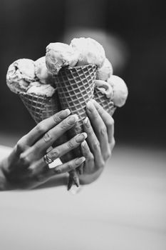 Crop of woman's hand holding delicious colorful ice cream, looking tasty, sweet, mouthwatering, perfect for summer heat while sunny day. Pretty nails with professional french manicure. Food concept.