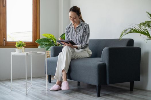 Woman enjoy with content social media application on digital tablet sitting on sofa at home