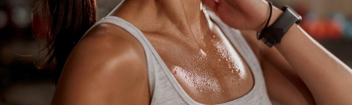 Close up of shoulders and neck fit female with sweat on skin after training, massaging neck muscles