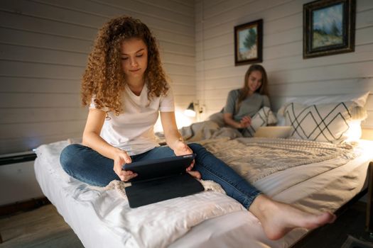 Two beautiful women lying in bed, holding and watching laptop