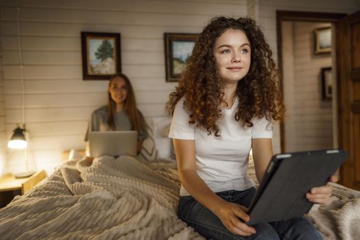 Two beautiful women lying in bed, holding and watching laptop