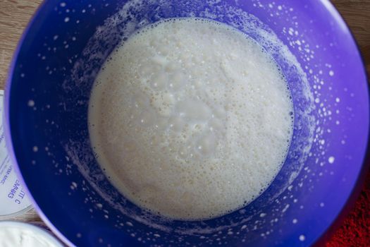 View of home made dough in big rounded plate for red cakes on table, preparing for cooking. Sweet bake on wooden table. Concept of bake and sweet food.