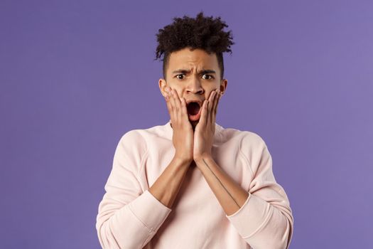 Oh gosh thats terrible. Portrait of shocked, speechless and worried young man express compassion finding out friend got in trouble, gasping open mouth and stare startled camera, touch face in shook.