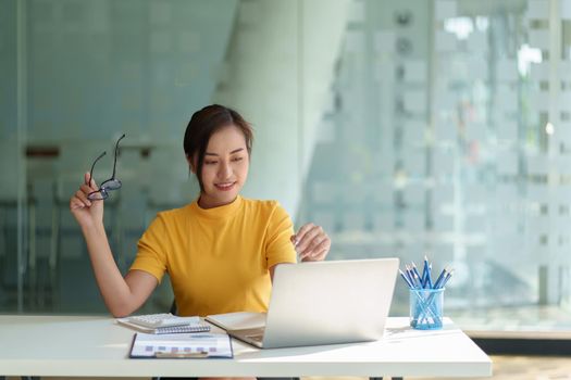 Business woman hand holding pen looking at bank savings account application on laptop. account or saving money or insurance concept