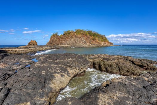 Playa Ocotal with Pacific ocean waves on rocky shore, El Coco Costa Rica. Famous snorkel beach. Picturesque paradise tropical landscape. Pura Vida concept, travel to exotic tropical country.