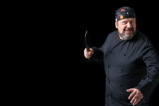 Portrait of cook with knife in hand with black background and copy space on the left side. Expressions of concept.