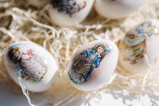 Close-up of different drawings on goose eggs for Easter festival. Eggs on hay. Hand made print. Spring hollidays. Easter concept.