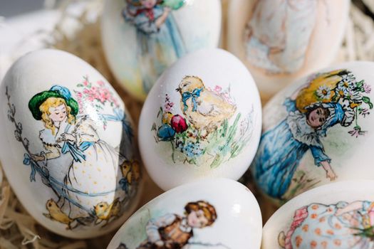 Close-up of different drawings on goose eggs for Easter festival. Eggs on hay. Hand made print. Spring hollidays. Easter concept.