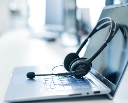 Call center operator desktop. Close-up of a headset on a laptop. Help desk. Workplace of a support service employee. Headphones with a microphone for voip on a computer keyboard