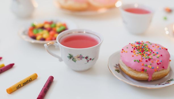 holiday, birthday party composition with colorful pink glazed donuts on white table, flatlay top view. 