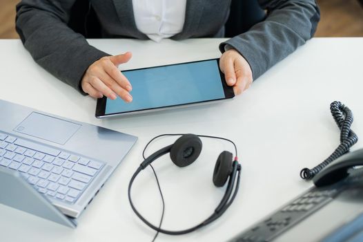 Close-up of the hands of a female office worker with a digital tablet. A faceless woman works as a call center operator