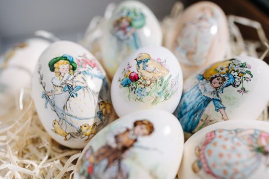 Close-up of different drawings on goose eggs for Easter festival. Eggs on hay. Hand made print. Spring hollidays. Easter concept.