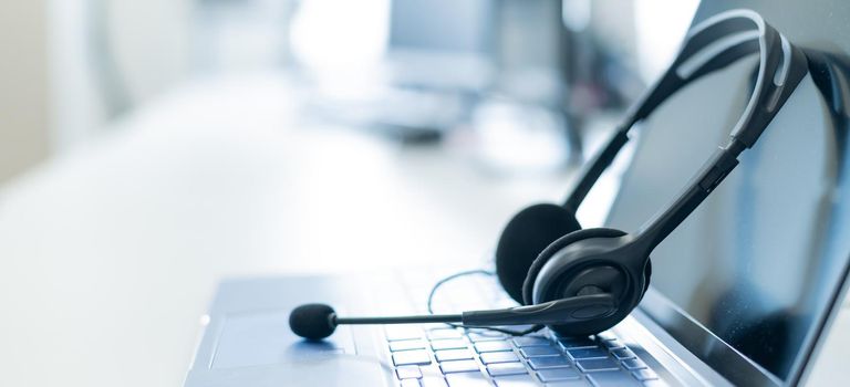 Call center operator desktop. Close-up of a headset on a laptop. Help desk. Workplace of a support service employee. Headphones with a microphone for voip on a computer keyboard