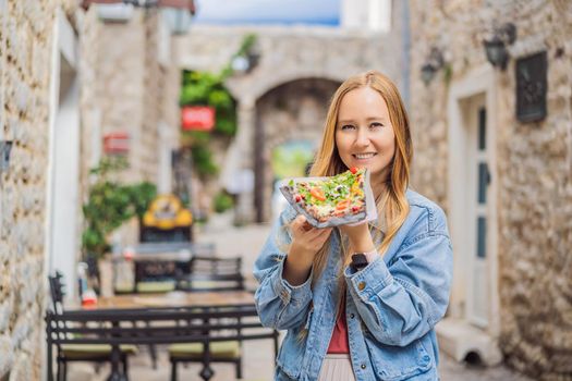 Young woman tourist eating traditional pizza in the old town of Budva. Travel to Montenegro concept.