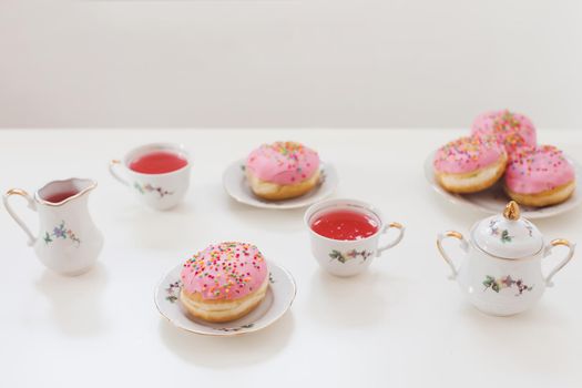 holiday, birthday party composition with colorful pink glazed donuts on white table, flatlay top view. 