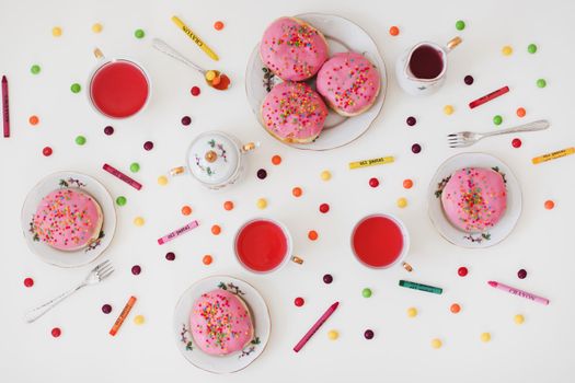 holiday, birthday party composition with colorful pink glazed donuts on white table, flatlay top view. 