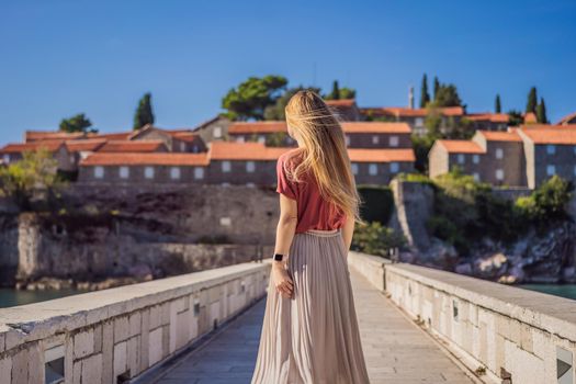 Woman tourist on background of beautiful view of the island of St. Stephen, Sveti Stefan on the Budva Riviera, Budva, Montenegro. Travel to Montenegro concept.