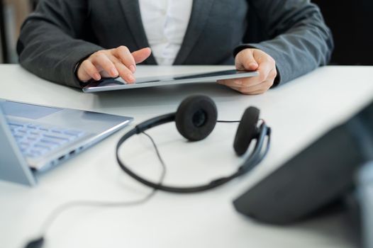 Close-up of the hands of a female office worker with a digital tablet. A faceless woman works as a call center operator