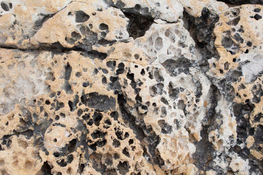 beige background natural stone with cracks and holes macro view