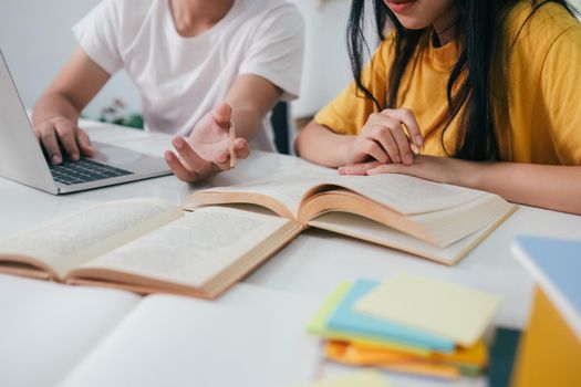 Learning, education and school concept. Young woman and man studying for a test or an exam. Tutor books with friends. Young students campus helps friend catching up and learning.
