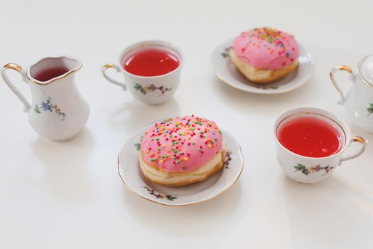 holiday, birthday party composition with colorful pink glazed donuts on white table, flatlay top view. 