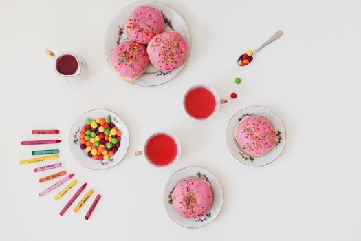 holiday, birthday party composition with colorful pink glazed donuts on white table, flatlay top view. 
