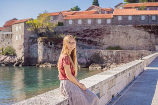 Woman tourist on background of beautiful view of the island of St. Stephen, Sveti Stefan on the Budva Riviera, Budva, Montenegro. Travel to Montenegro concept.