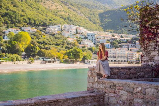 Woman tourist on background of beautiful view of the island of St. Stephen, Sveti Stefan on the Budva Riviera, Budva, Montenegro. Travel to Montenegro concept.