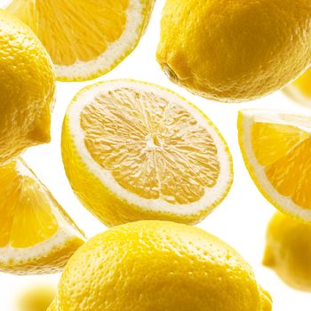 Yellow lemons levitate on a white background.