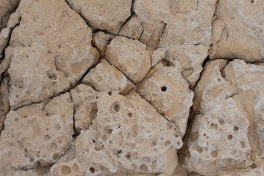 beige background natural stone with cracks and holes macro view