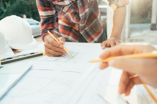 Hands of an architect and an engineer pointing at the architectural plan. they have a coordination meeting to make sure everything works