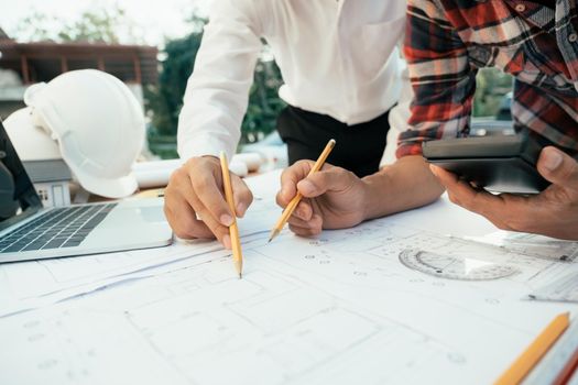 Hands of an architect and an engineer pointing at the architectural plan. they have a coordination meeting to make sure everything works