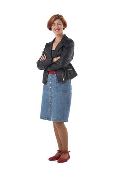 Full body shoot of redhead woman in pencil jeans skirt and leather jacket standing with arms folded, isolated on white background