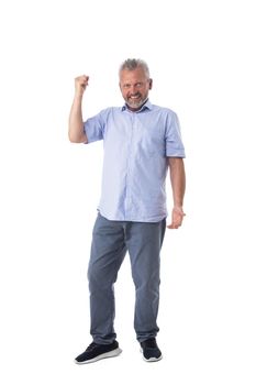 Full length portrait of excited mature man in casual clothes holding fist isolated on white background