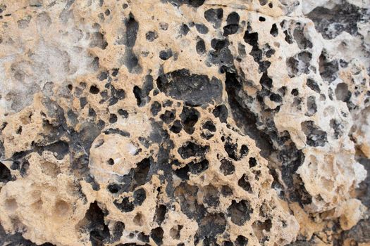 beige background natural stone with cracks and holes macro view