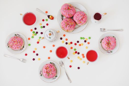 holiday, birthday party composition with colorful pink glazed donuts on white table, flatlay top view. 