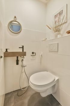 The interior of the bathroom is lined with white tiles, which has a marble sink and a hinged toilet