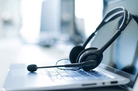 Call center operator desktop. Close-up of a headset on a laptop. Help desk. Workplace of a support service employee. Headphones with a microphone for voip on a computer keyboard