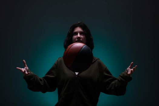 Teenage girl with basketball. Studio portrait with neon blue colored background.