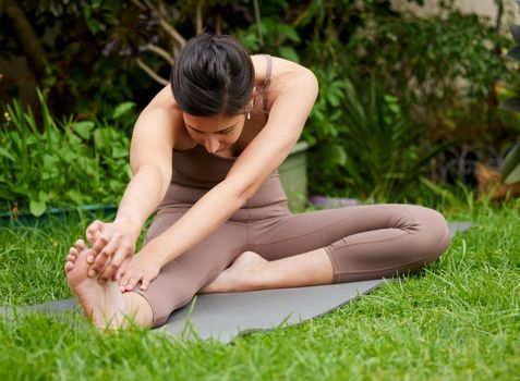 Shot of a young woman stretching her legs while exercising outdoors.