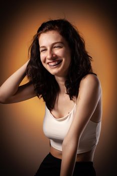 Teenage girl with dental braces. Studio portrait on neon orange colored background.