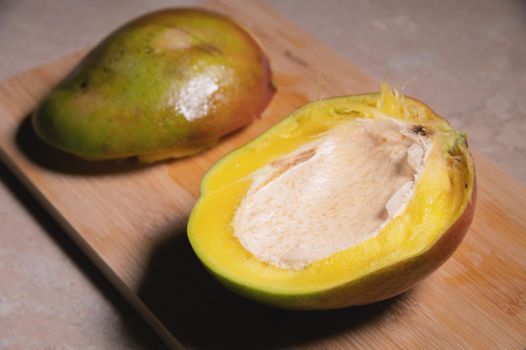 Close-up shallow depth of field cutaway mango kent on a cutting board. Mango home cooking.
